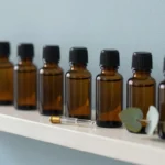 Amber aromatherapy oil bottles and a brass pipette on a shelf